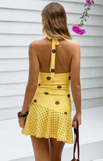Rear view of a yellow polka dot mini dress with a halter neck tie and open back The bodice has large dots, the skirt has smal