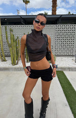 Full length view of a black sheer high neck sleeveless top with a cropped, flowy fit and asymmetric hem