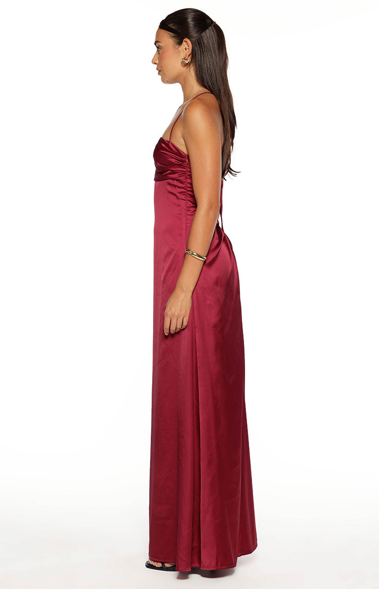Side view of a burgundy satin maxi dress with a ruched bust and thin spaghetti straps