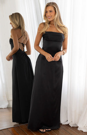 Model in an elegant black satin floor length dress with a square neckline and halter straps. A sophisticated choice for a Formal evening