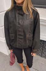 Distressed brown PU jacket with a high funnel neck, button placket, and two front flap pockets