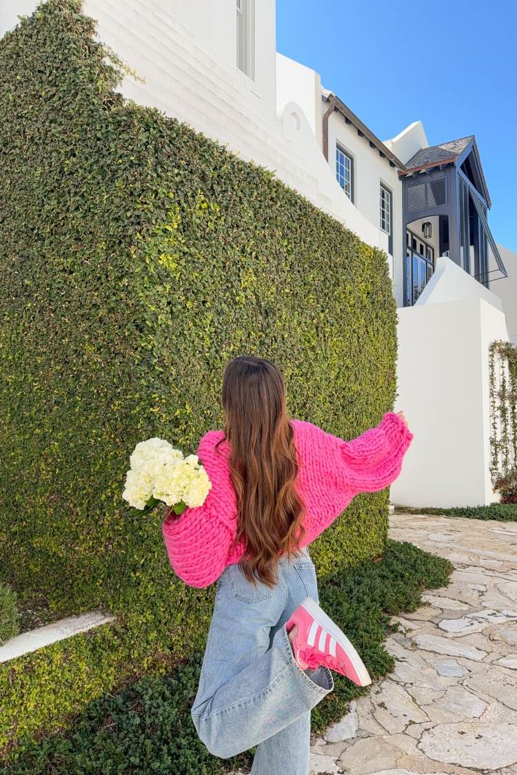 Rear view of a bright pink chunky knit cardigan with an oversized fit and voluminous long sleeves