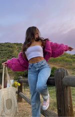 Open front view of a vibrant pink chunky knit cardigan with voluminous sleeves and a relaxed fit