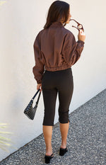 Rear view of a chocolate brown bomber jacket with a collar, elasticated hem, and voluminous long sleeves with elastic cuffs