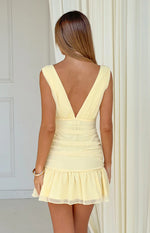 Rear view of a yellow ruched mini dress with a deep V-back and ruffled hem