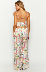 Rear view of white satin wide-leg pants with a colourful Roma print featuring fruits and palm trees