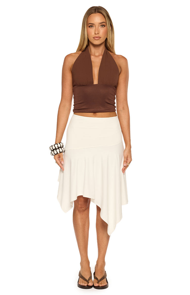 White asymmetrical midi skirt with a fitted waist and a flowy draped hem