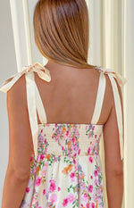 Rear view of a yellow floral mini dress with cream tie-up shoulder straps and a smocked back bodice