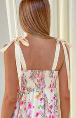 Rear view of a yellow floral mini dress with cream tie-up shoulder straps and a smocked back bodice