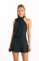 Black mini dress with a white polka dot print- featuring a high halter neck and a flowing A-line silhouette.