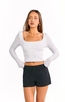 Our model is wearing a pair of black high-waisted shorts with a small white polka dot pattern.