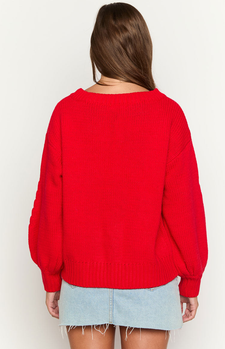 Rear view of a red ribbed knit sweater with a wide neckline and voluminous long sleeves gathered at the cuffs
