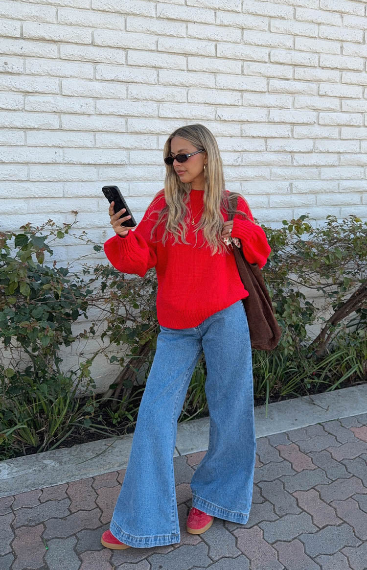 Full view of a bright red chunky knit sweater with a relaxed fit and voluminous long sleeves