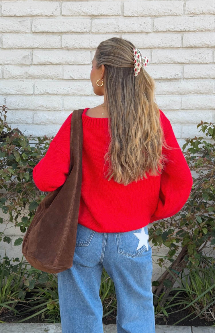 Back of a red knit sweater with a wide boat neckline and slightly voluminous long sleeves
