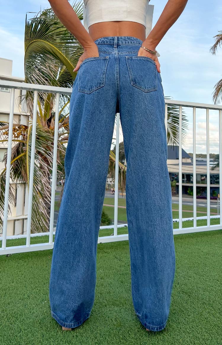 Rear view of mid-wash blue jeans featuring two back patch pockets and a loose, wide-leg cut