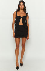 Black chiffon top with a sweetheart neckline, twisted knot bust, underbust cutout, ruffled shoulder straps, and flowy front panels