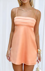 Close-up of the pleated bust and sheer mesh panel on an orange satin mini dress