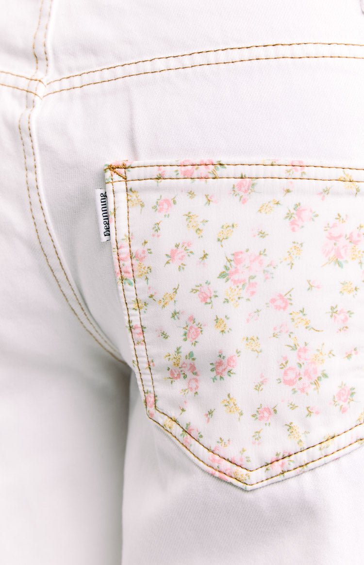 Close-up of the white jeans back pocket with a pink and yellow floral pattern and tan stitching