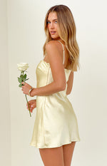 Side view of a pale yellow satin mini dress with adjustable spaghetti straps and a flared mini skirt