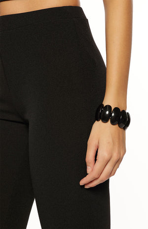 A close-up shot of our model wearing solid black capri-length tight pants with an elastic waist.