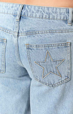 Detail shot of the back pocket on light wash denim jeans with a star outline stitched in tan