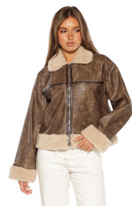 Close-up of the brown faux leather aviator jacket with cream shearling trim and silver zipper