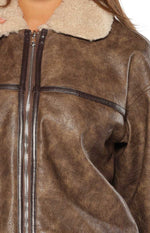 Close-up of the distressed brown faux leather aviator jacket with cream shearling collar and dark brown piping