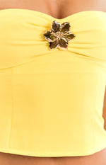 Close-up of the gold hibiscus trim on the ruched bust of a yellow strapless top