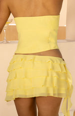 Rear view of a yellow strapless top showing the fitted bodice construction and curved hem
