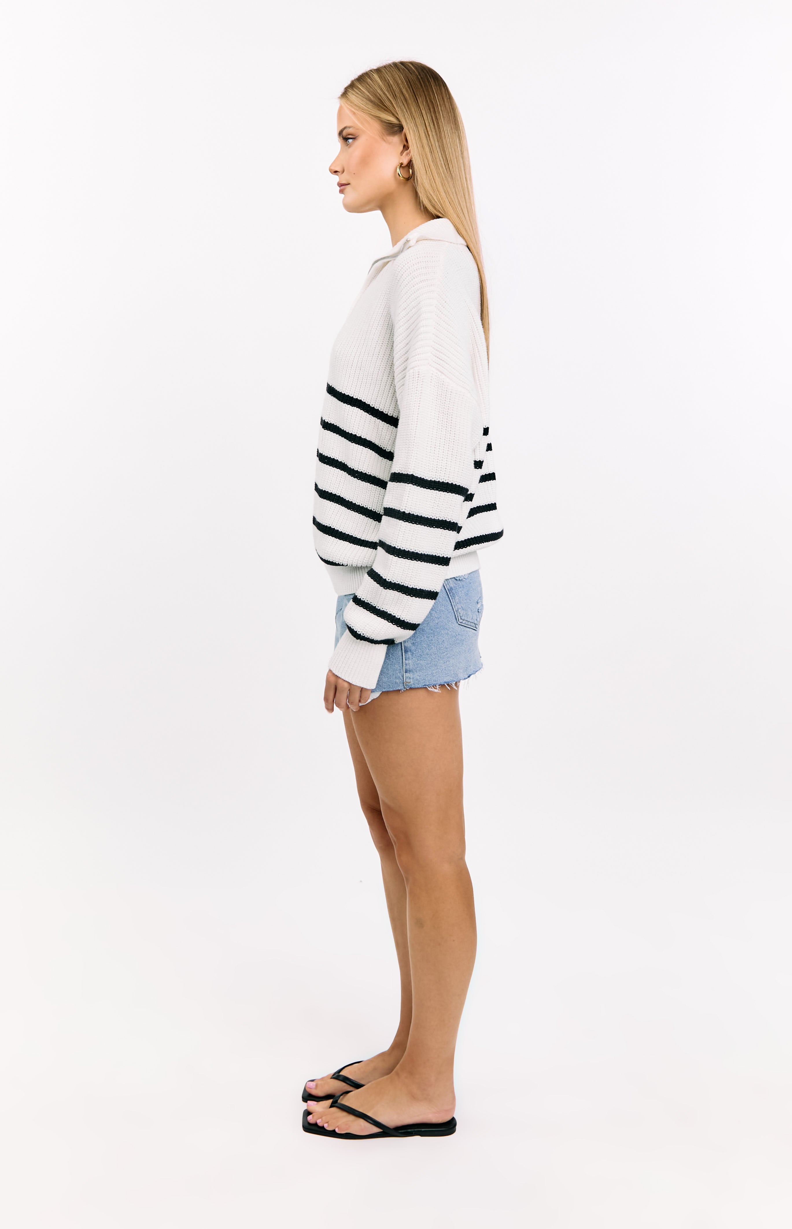 Side view of a cream knit quarter zip jumper with black horizontal stripes and a relaxed fit
