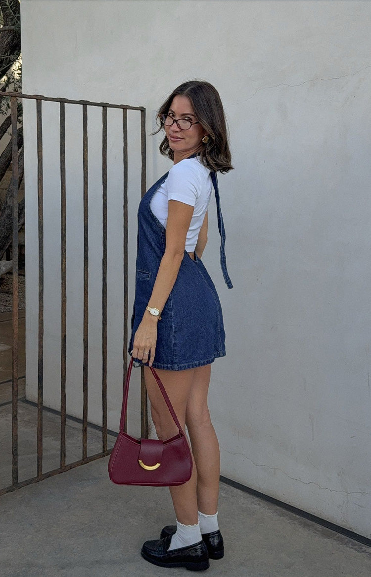 Side view showing the open back and long ties of the denim halter neck mini dress with a side pocket
