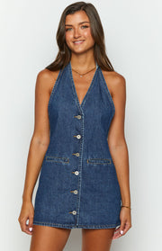Close-up front view of a blue denim halter neck mini dress with a deep V-neck, full button-front, and two pockets