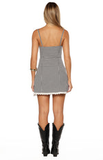 Back view showing the square neckline, thin straps, and white lace hem of a black gingham mini dress