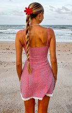 Rear view of a red gingham mini dress with thin spaghetti straps and white lace trim hem