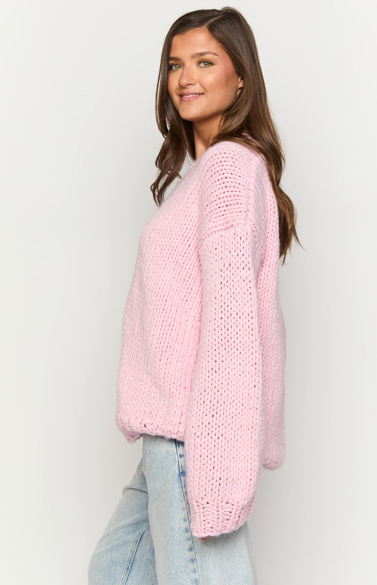 Side view of a light pink chunky knit sweater with an off-shoulder neckline and long oversized sleeves