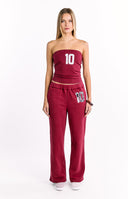 A pair of red wide-leg sweatpants with a drawstring waist featuring a number 10 applique with a black and white cow print pattern on the left thigh.