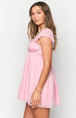 Side view of a pink mini dress with ruched short sleeves and an empire waist flowing into a layered skirt