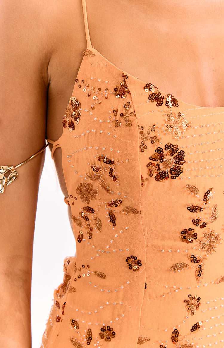 Close-up of the orange mini dress showing the side cutouts with lacing and intricate floral sequin and bead patterns