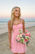 Pink crepe mini dress with a ruched bust, thin spaghetti straps, and a ruffled hem