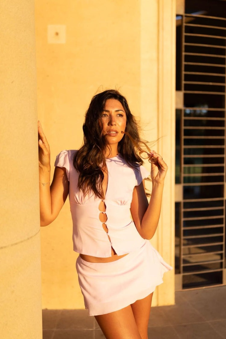 Front and side view of a pink woven mini skirt with a slight A-line cut and soft, flowy hem