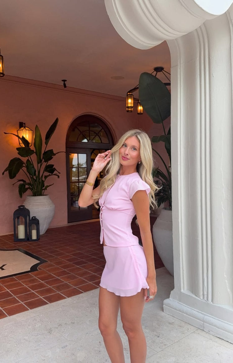 Fitted pink woven top with a keyhole cutout, short cap sleeves, and button-front detail