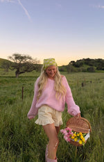 Rear view of a light pink chunky knit sweater with an off-shoulder neckline