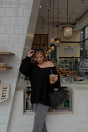 Black chunky knit sweater with an off-shoulder neckline, showing the prominent knit texture
