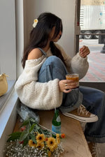 Cream chunky knit sweater with a wide boat neck, dropped shoulders, and voluminous cuffed sleeves