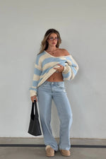 Light blue and white striped chunky knit sweater with a wide off-shoulder neckline and oversized sleeves