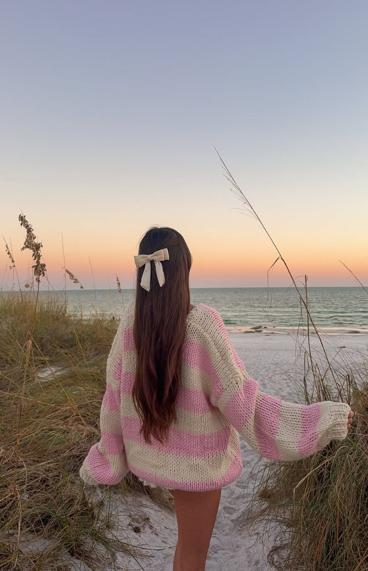 Rear view of a pink and cream striped chunky knit sweater with an oversized fit and wide sleeves