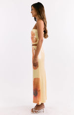 Side view of a yellow sequin maxi skirt showing the large orange floral print and straight silhouette