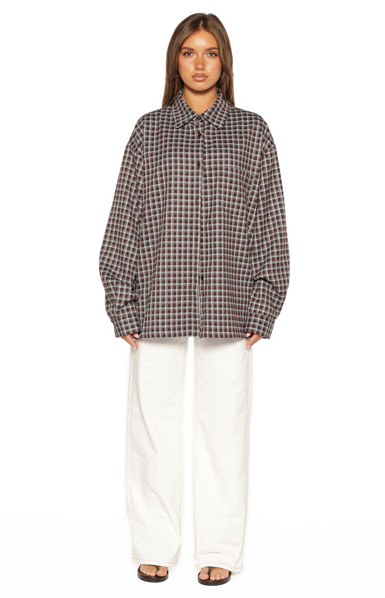 Front view of an oversized brown and blue plaid long sleeve button-up shirt with a collar and single chest pocket
