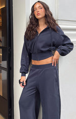 Side view of a navy cropped zip hoodie sweater with drawstring hood, full zip, and cinched elasticated hem