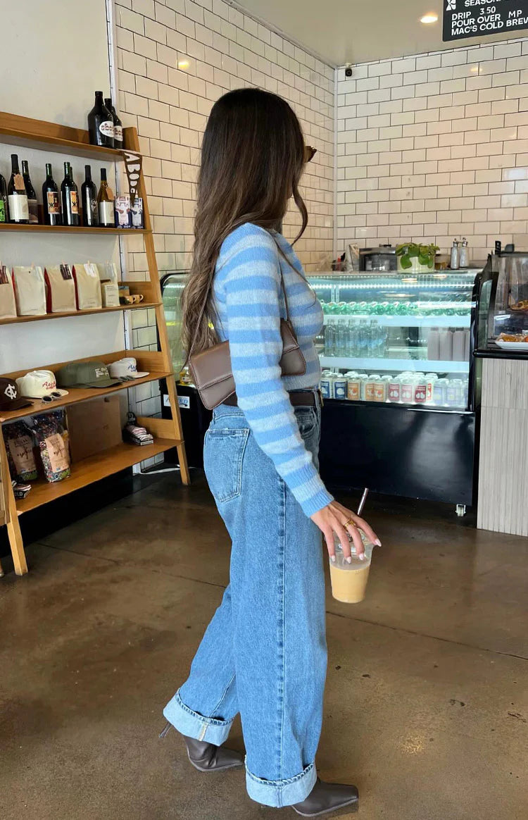 Close-up of a blue and white striped knit sweater with a partially unzipped front and cropped hem